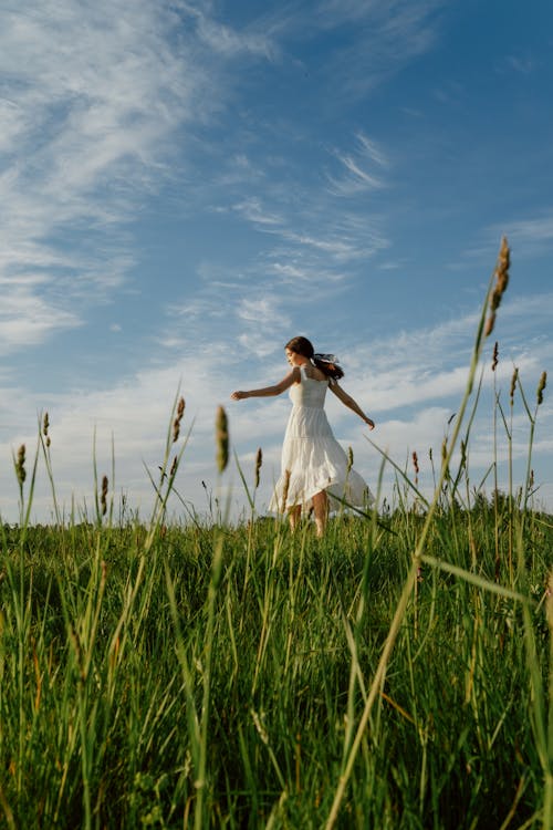 Free Woman in White Dress Dancing on the Meadow Stock Photo