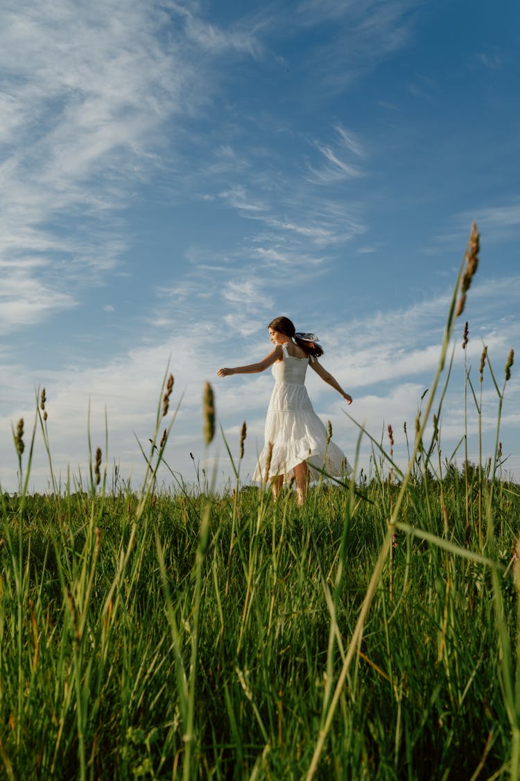 Woman In White Dress Dancing On The Meadow