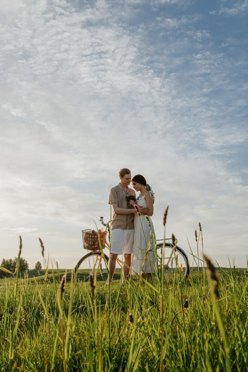 Couple Embracing in Meadow Next to Bicycle