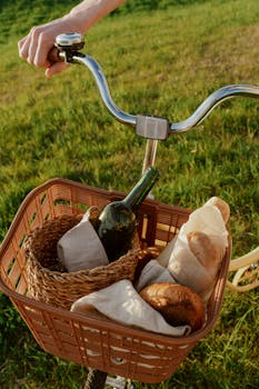 Bicycle basket in a meadow with wine and bread, perfect for a summer picnic.