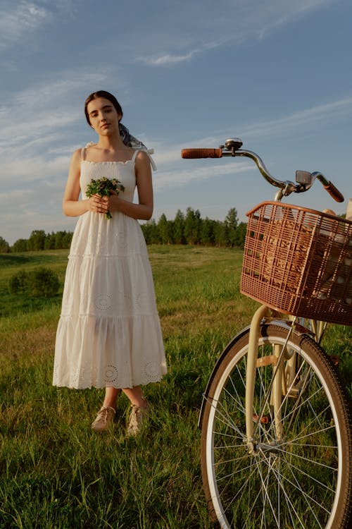 Free Girl in a White Dress with a Bicycle on a Meadow Stock Photo