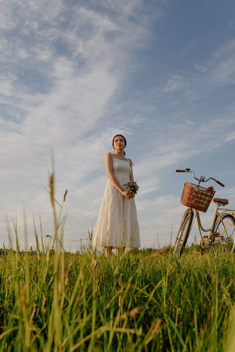 Woman In White Dress And Bicycle On A Meadow