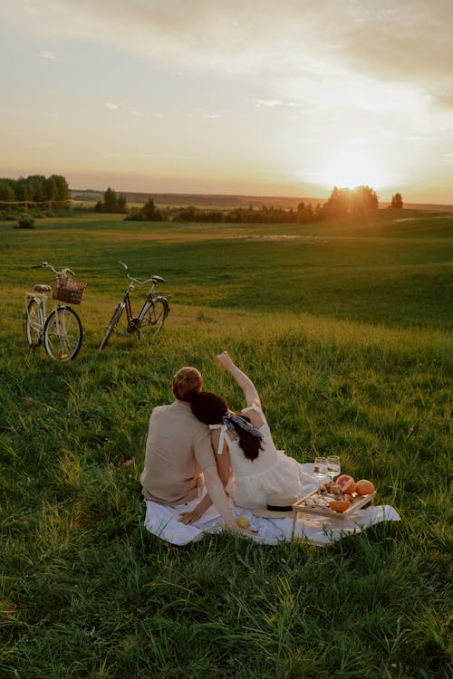 A Couple Sitting on the Grass Field