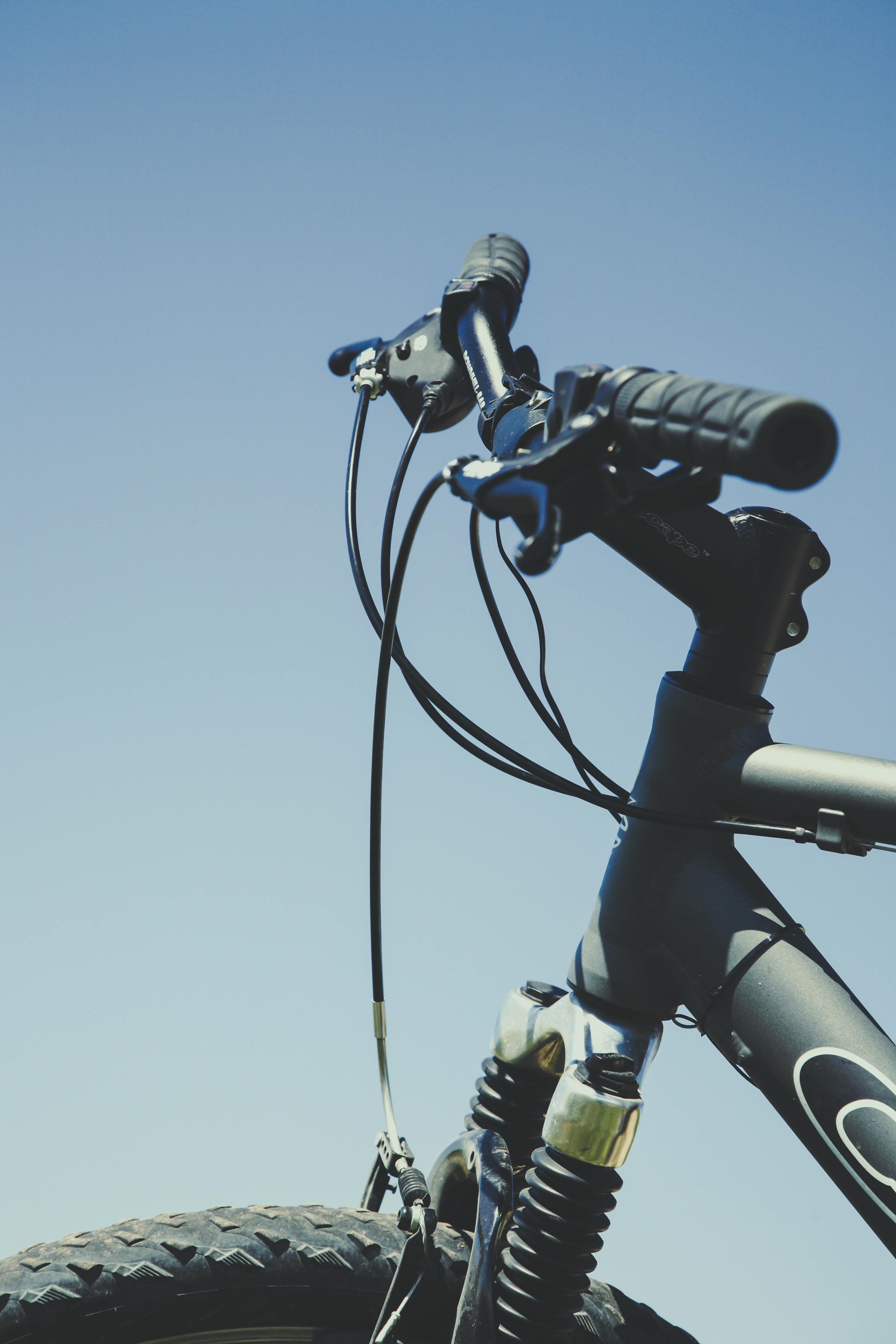 Close-up of a mountain bike handlebar with a clear blue sky background, emphasizing outdoor adventure.