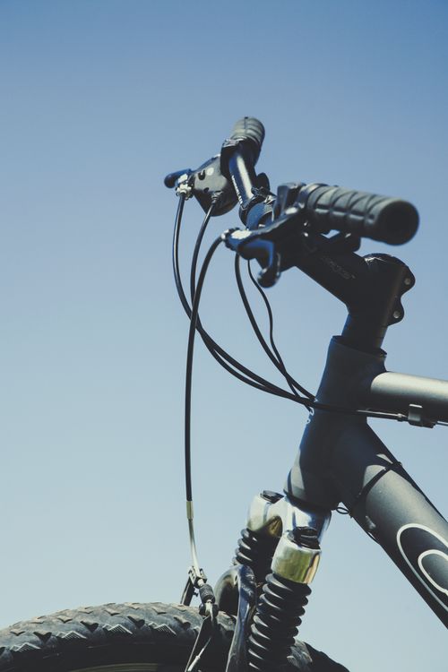 Free Close-up of a mountain bike handlebar with a clear blue sky background, emphasizing outdoor adventure. Stock Photo