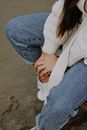 Woman in White Sweater and Blue Denim Jeans Sitting on Brown Wooden Bench