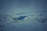 冬日黄昏时分，阴沉的天空下，白雪覆盖的山峰呈现出一片宁静的景色