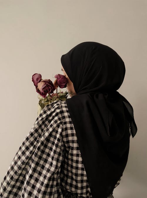 A Woman in Black Hijab Holding Bouquet of Flowers