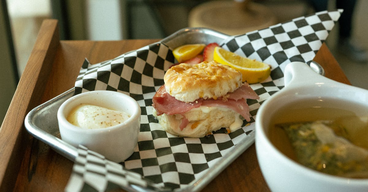 A delicious ham and cheese biscuit served with lemon slices and tea, perfect for breakfast.