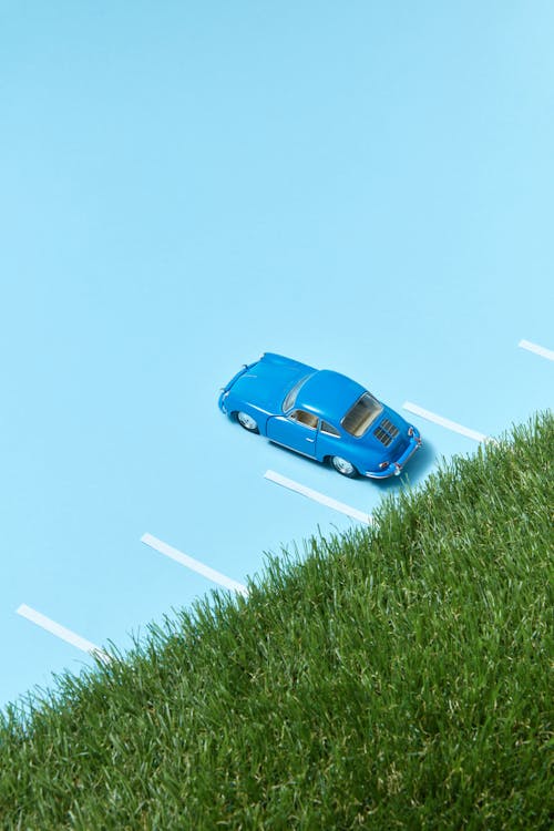A Blue Toy Car Parked Near Green Grass Field