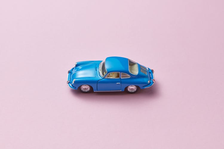 A Blue Miniature Toy Car On Pink Background