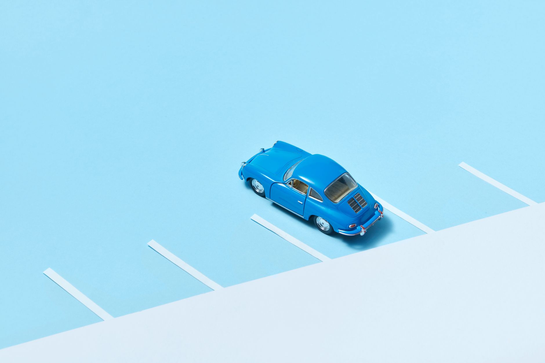 A minimalist scene featuring a vintage blue toy car parked in a lot, captured with high contrast.