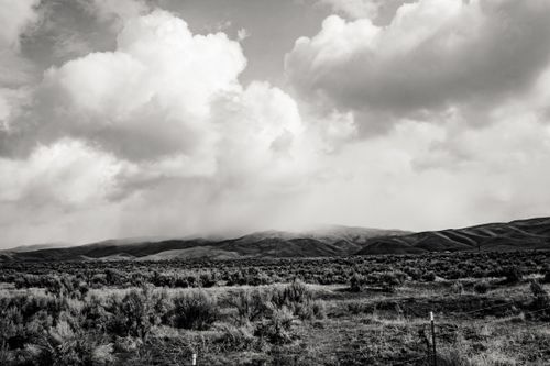 Free Captivating black and white landscape of cloudy hills and serene fields. Stock Photo