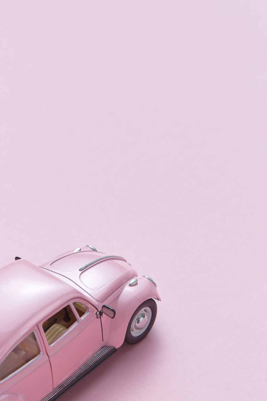 Miniatura de carro rosa sobre fundo rosa