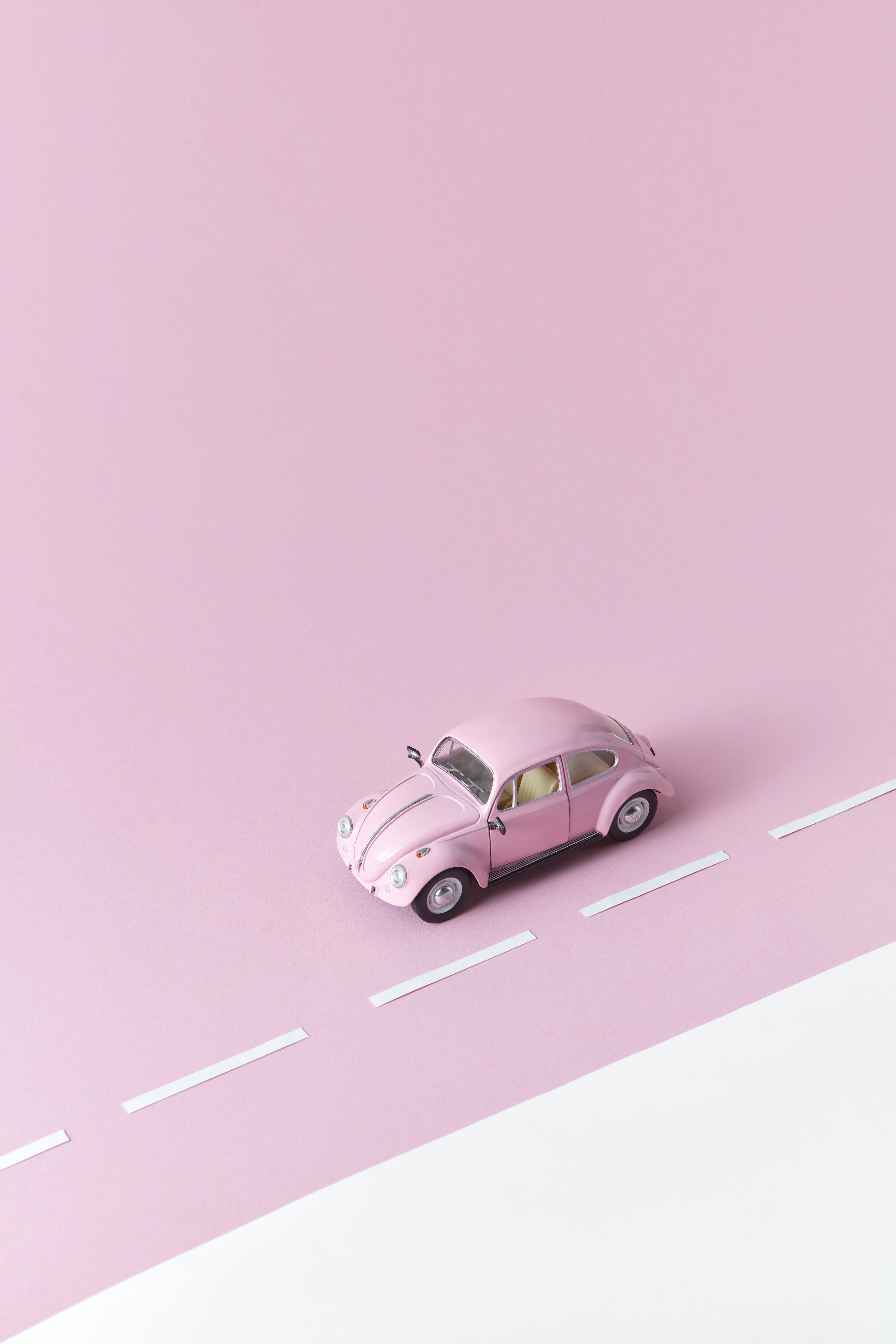 photograph of a pink miniature car beside white paper strips