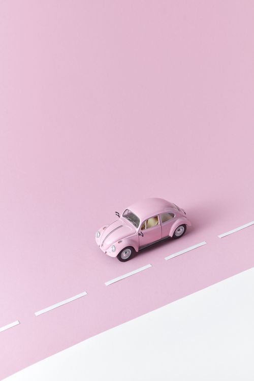 Free A pink toy car on a minimalistic pastel pink surface, representing simplicity and playfulness. Stock Photo