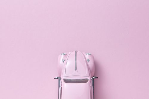 Free Top view of a pink vintage toy car on a pastel pink background, perfect for automotive themes. Stock Photo