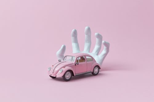 Free Photo of a White Hand Behind a Pink Car Toy Stock Photo