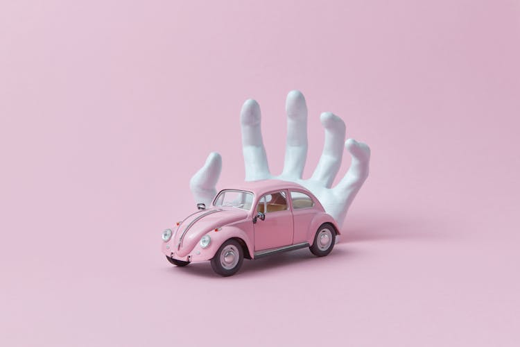 Photo Of A White Hand Behind A Pink Car Toy