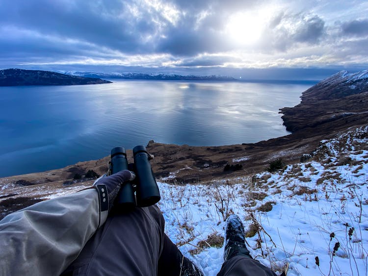 Person Holding A Binoculars Near A Body Of Water