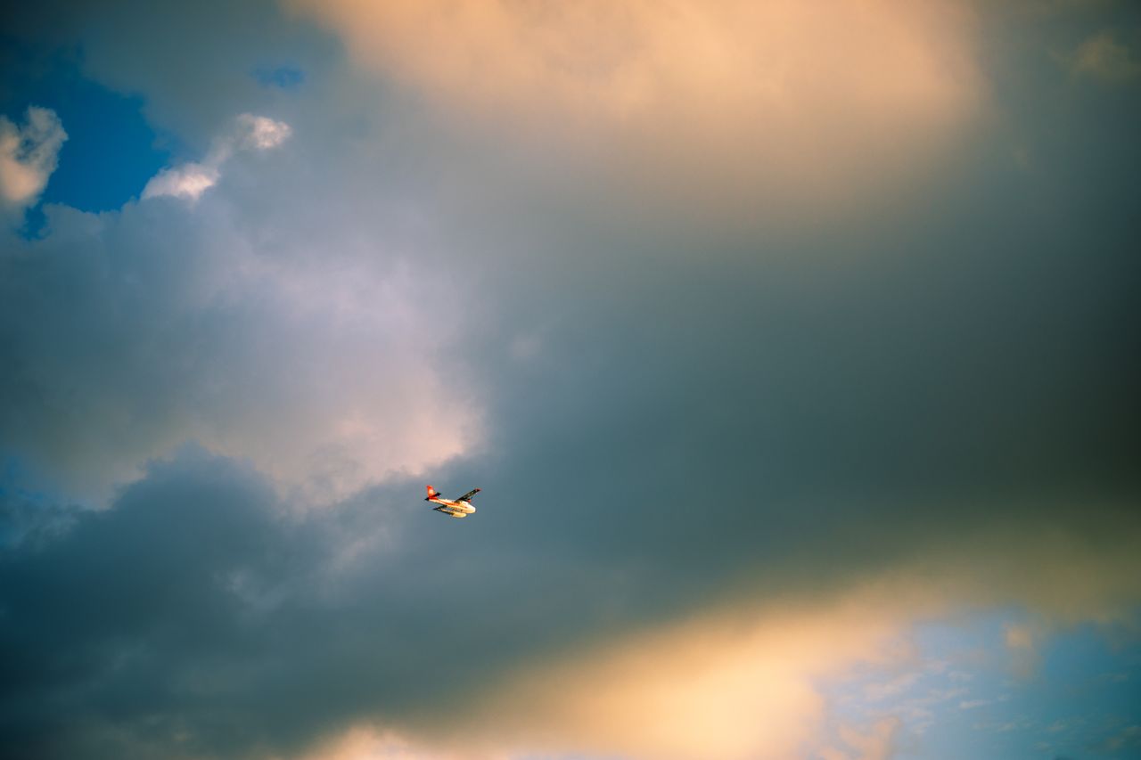 a lone airplane soars through a dramatic sky filled with dark clouds a