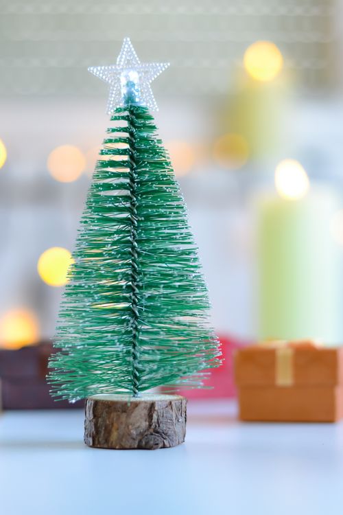 Free A festive miniature Christmas tree with a star topper, perfect for holiday decoration. Stock Photo