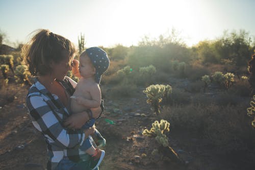Free Vrouw In Wit Zwart En Grijs Geruit Overhemd Met Baby Met Blauwe Pet Stock Photo