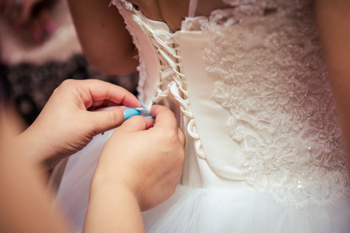 A bridal store assistant laces up a wedding gown's bodice