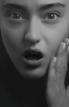 Close-up black and white portrait capturing a woman's shocked expression.