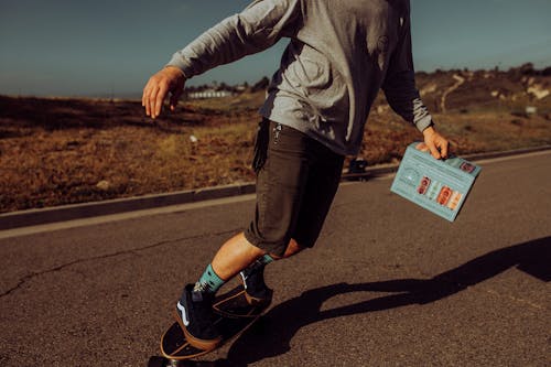 Free A Person Riding a Skateboard while Holding a Box of Beer Stock Photo