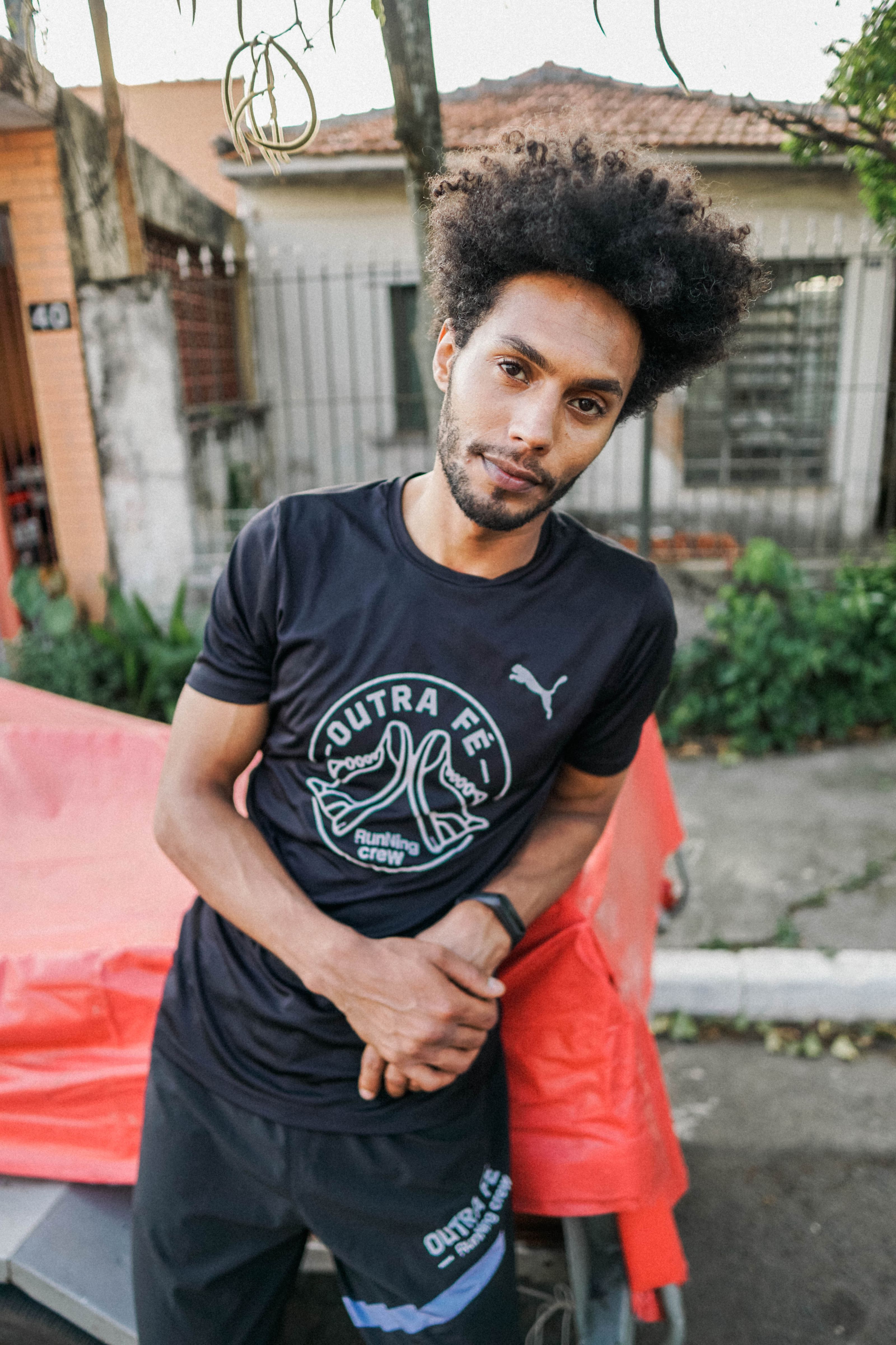 Um homem confiante com cabelo afro em um ambiente urbano descontraído em São Paulo, Brasil.