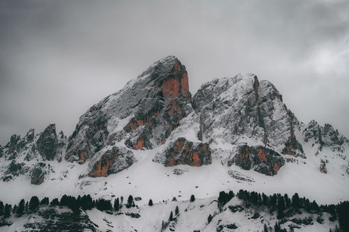 Free Majestic snow-capped mountains with trees, under an overcast sky, showcasing natural beauty. Stock Photo