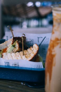 Close-up of a grilled sandwich served on a tray with iced coffee, perfect for lunch in a trendy setting.
