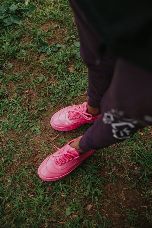 Free A Person in Pink Sneakers Standing on Green Grass Stock Photo