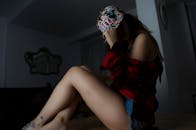 一位戴着花卉帽子、穿着休闲装的时尚年轻女性坐在室内，身上有纹身