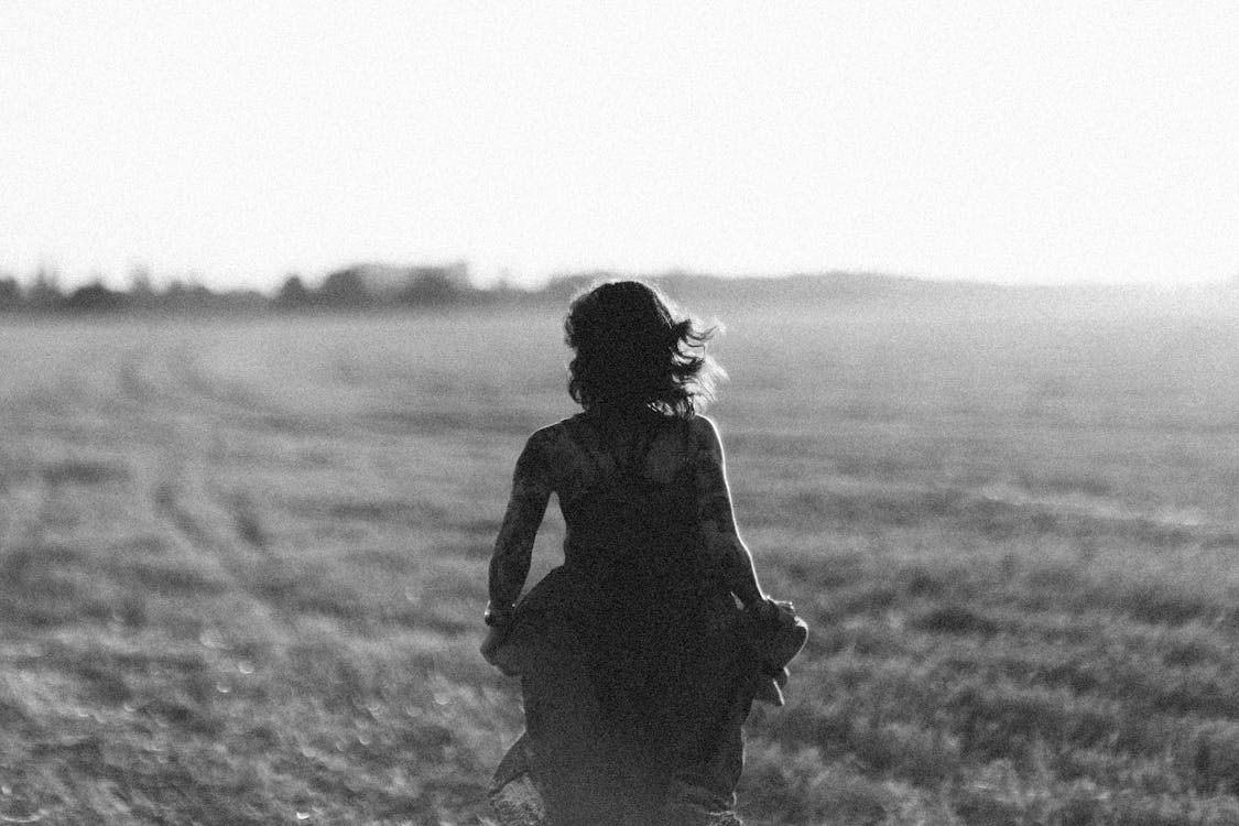 Grayscale Photo of Woman Running on Field · Free Stock Photo