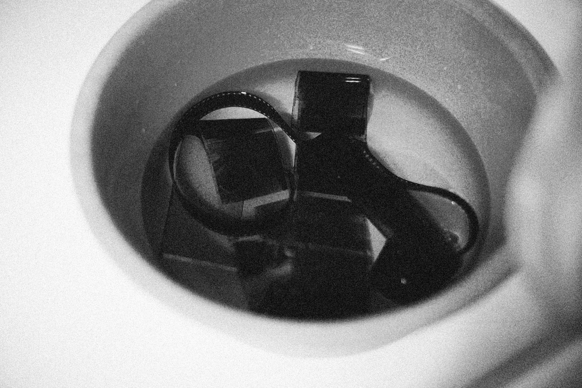 Close-up of film negatives soaking in a solution, showcasing the film development process in grayscale.