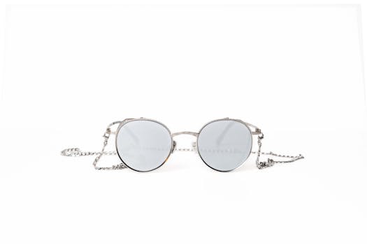 Round sunglasses with silver chain, perfect for a minimalist fashion look on a white background.