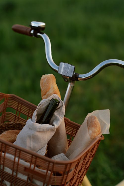 Free Bottle of Wine and Baguettes in Picnic Basket Hanging on Bike Handlebar Stock Photo