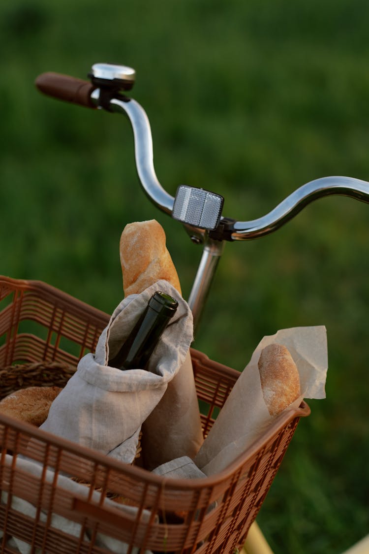 Bottle Of Wine And Baguettes In Picnic Basket Hanging On Bike Handlebar