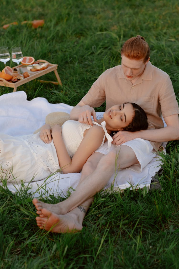 Young Couple Spending Time Together At Picnic In Green Meadow