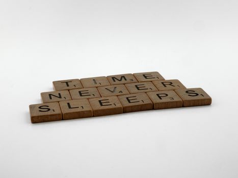 Scrabble tiles forming 'Time Never Sleeps' on a minimalistic white surface.
