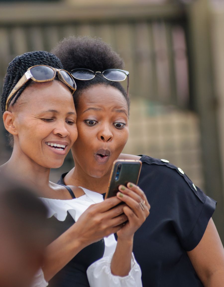 Deux jeunes femmes regardent, étonnées, une vidéo sur un smartphone