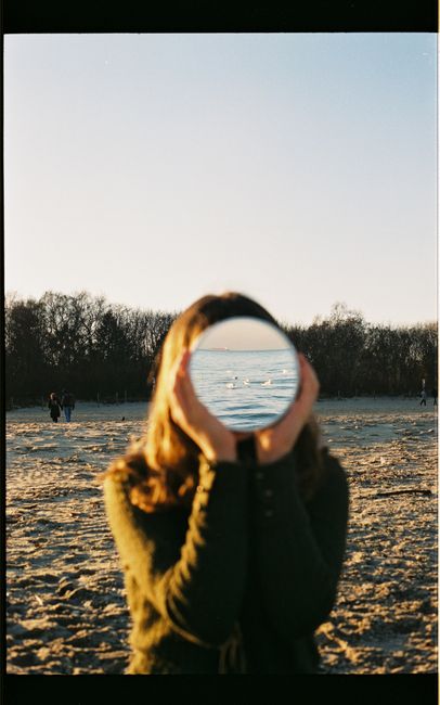 A creative beach photo with a mirror reflecting the sea view, creating a surreal illusion.