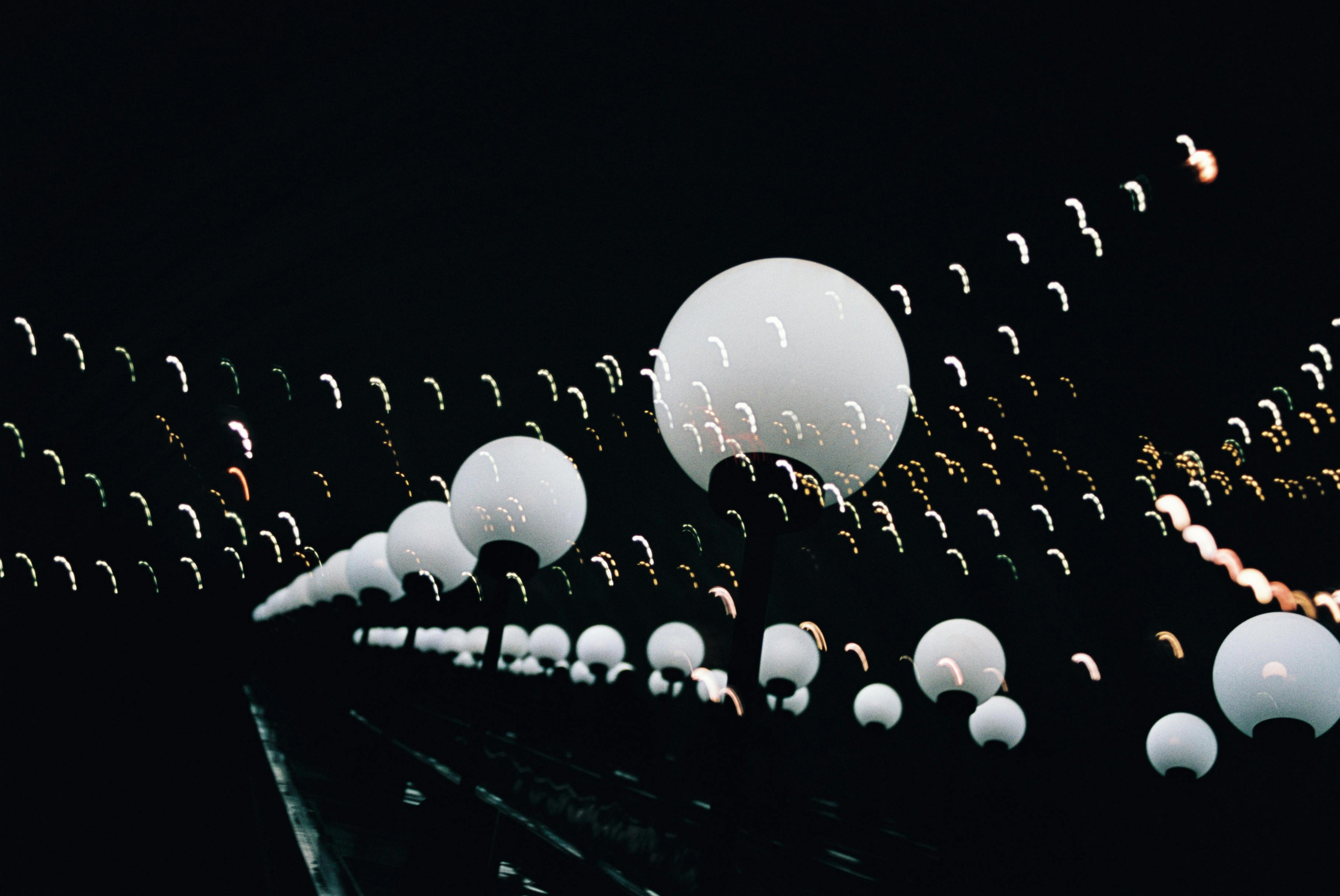 Abstract night scene featuring glowing spherical lights forming a path on a bridge.