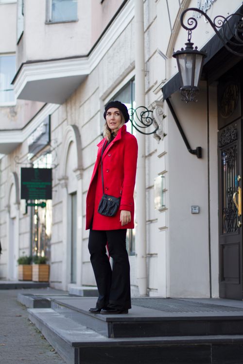Free Stylish woman in red coat and black hat standing on urban street in daylight. Stock Photo