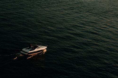 Free A speedboat cruising through calm waters, captured from above at sunset. Stock Photo