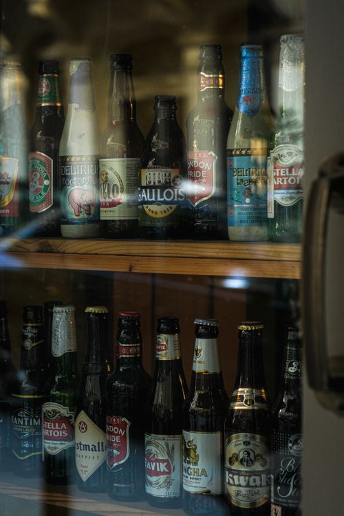 Free Collection of various beer bottles arranged in a glass cabinet highlighting diverse brands and labels. Stock Photo
