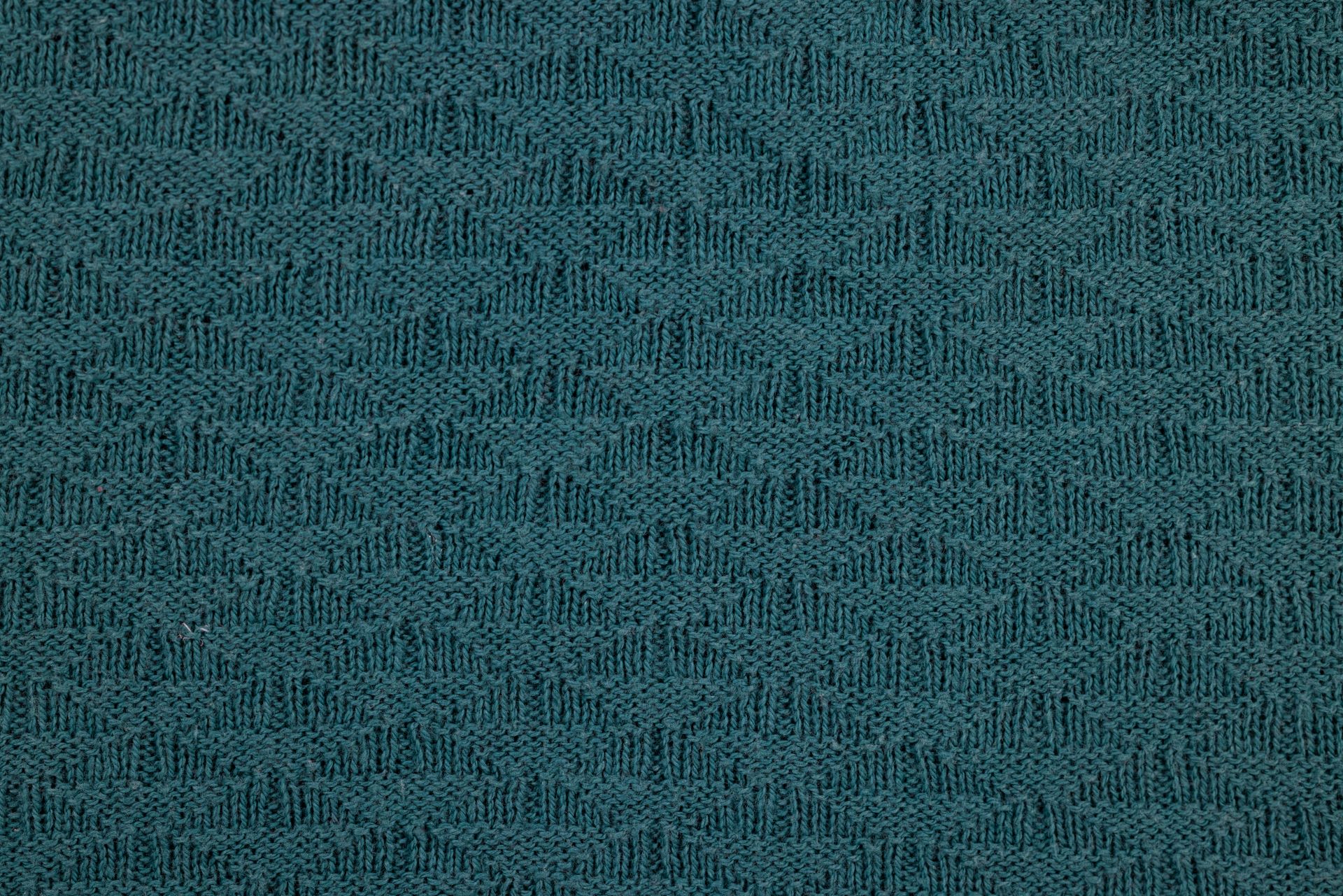 High-resolution close-up of teal textured knitted fabric featuring a chevron pattern, perfect for backgrounds.