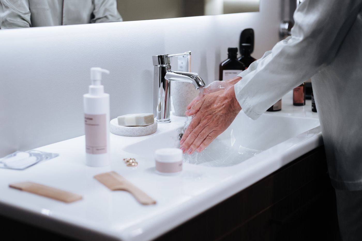 Hands being washed under running water at a clean bathroom sink before a personal care routine